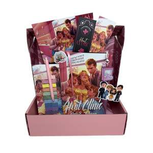 The Heat Clinic Special Edition book box items are shown spilling out of a pink mailing box. The book box includes the hardcover, an annotation tab and pen set, 2 vinyl stickers, 2 art prints, 2 matching bookmarks, and an acrylic shaker keychain.