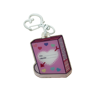 The back side of an acrylic shaker keychain shaped like a box of candy hearts including a to and from field and an ingredients list.