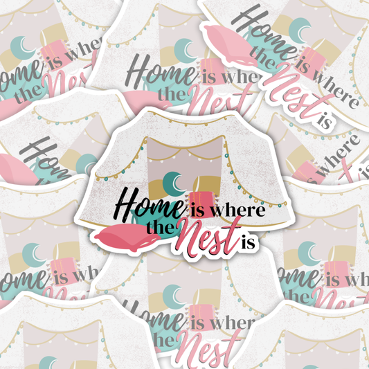 A vinyl omegaverse themed sticker that says "home is where the nest is" with a pillow fort full of teal, pink, and yellow pillows and string lights.
